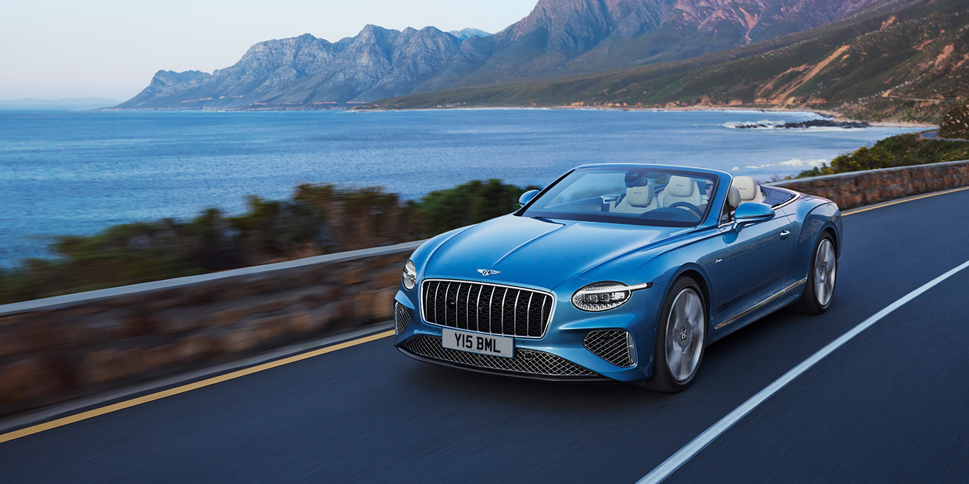 Bentley Adelaide New Bentley Continental GTC Azure convertible in Light Windsor blue paint with 22 inch Azure wheels and chrome grill, driving dynamically by the sea