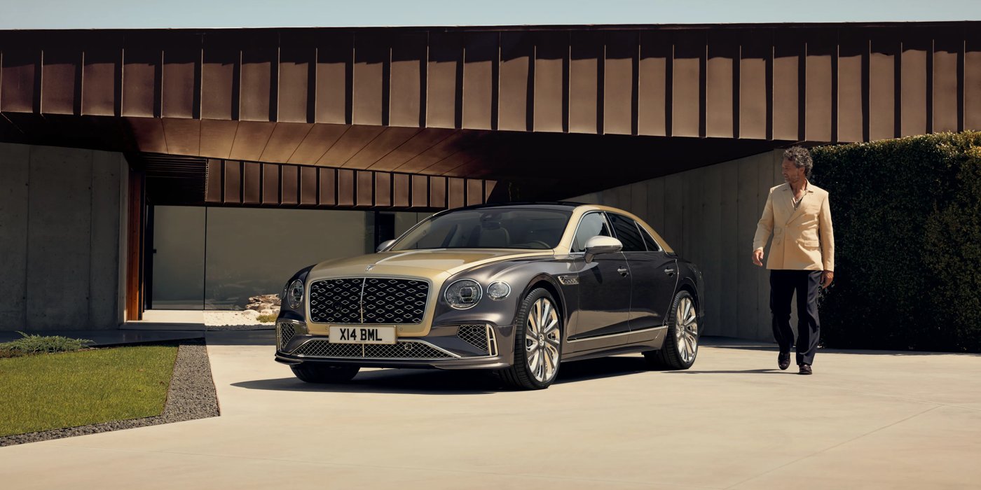 Bentley Adelaide Bentley New Flying Spur Mulliner V8 hybrid sedan front three quarters in Rose Gold over Magnetic paint, parked near modern home