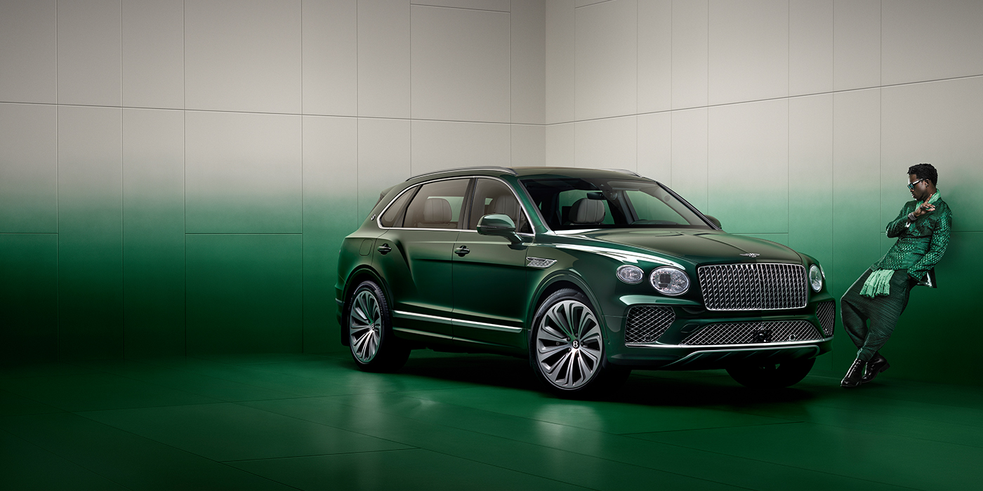 Bentley Adelaide Wisdom K leans against wall next to Bentley Bentayga Extended Wheelbase Atelier Edition SUV in Light Emerald green paint