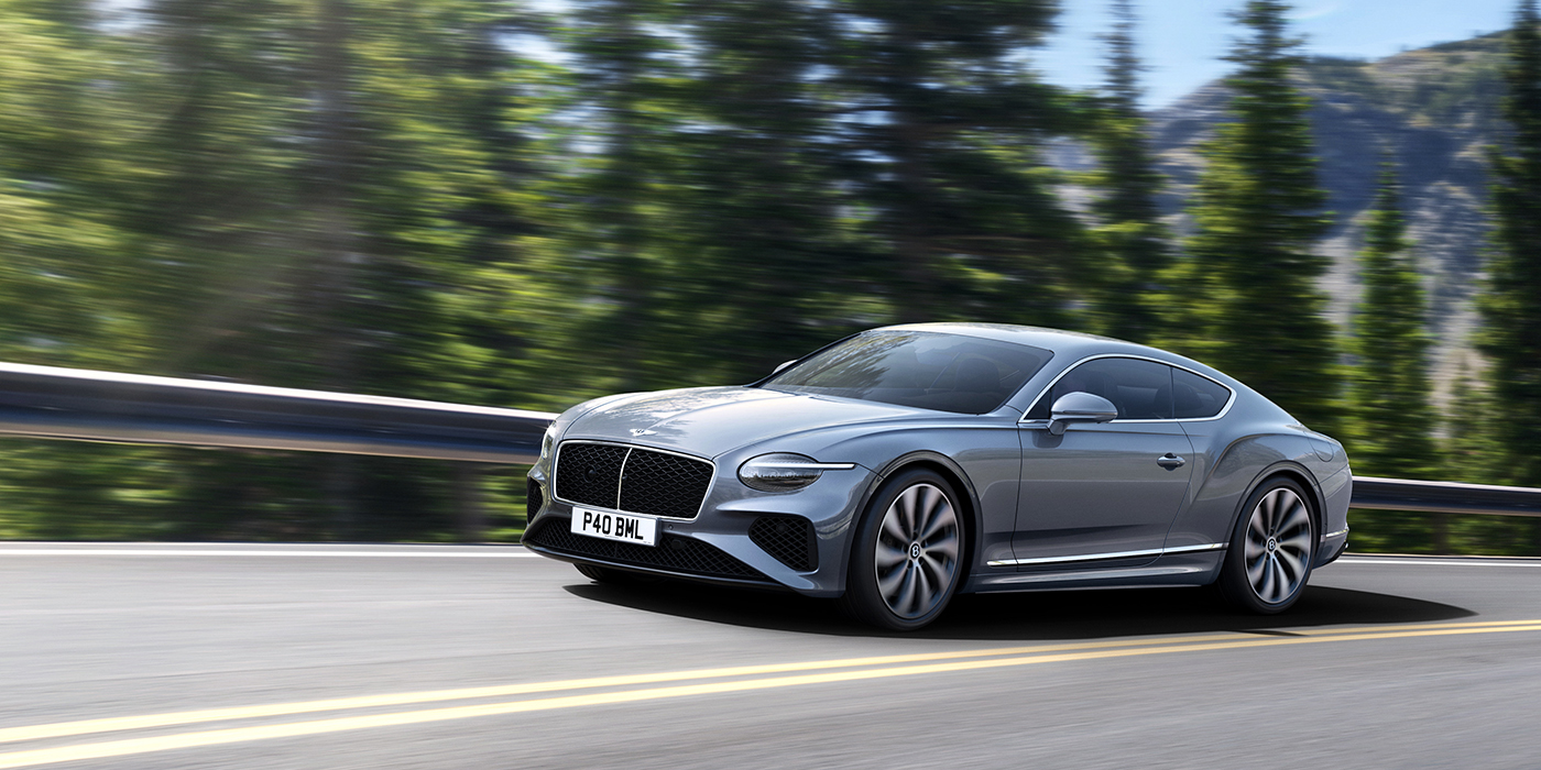 Bentley Adelaide New Bentley Continental GT coupe in Silverlake paint and 22 inch ten-spoke wheels, driving dynamically on a tree-lined road in the sunshine