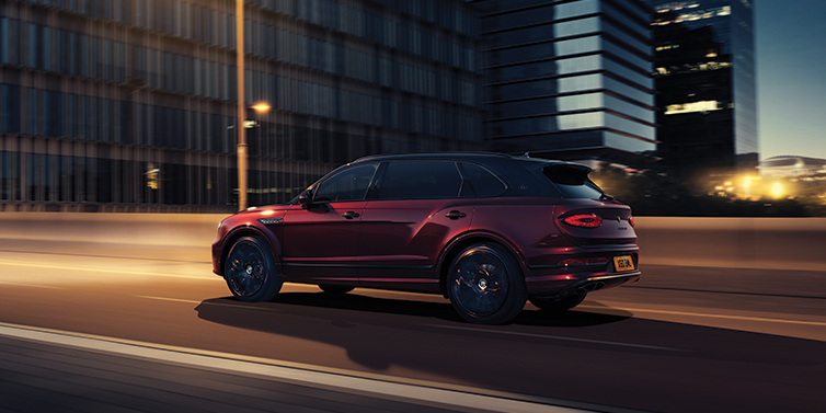Bentley Adelaide Bentley Bentayga Extended Wheelbase Mulliner SUV in Cricket Ball red paint driving dynamically in city at night